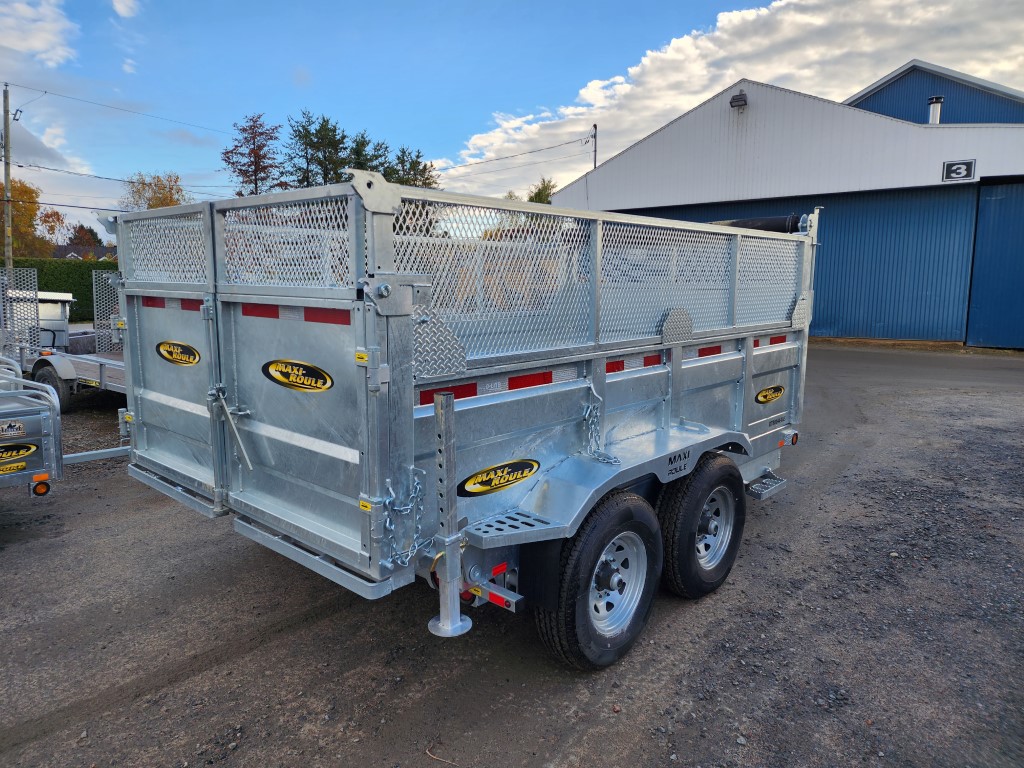 Une remorque à benne basculante est garée devant un bâtiment.