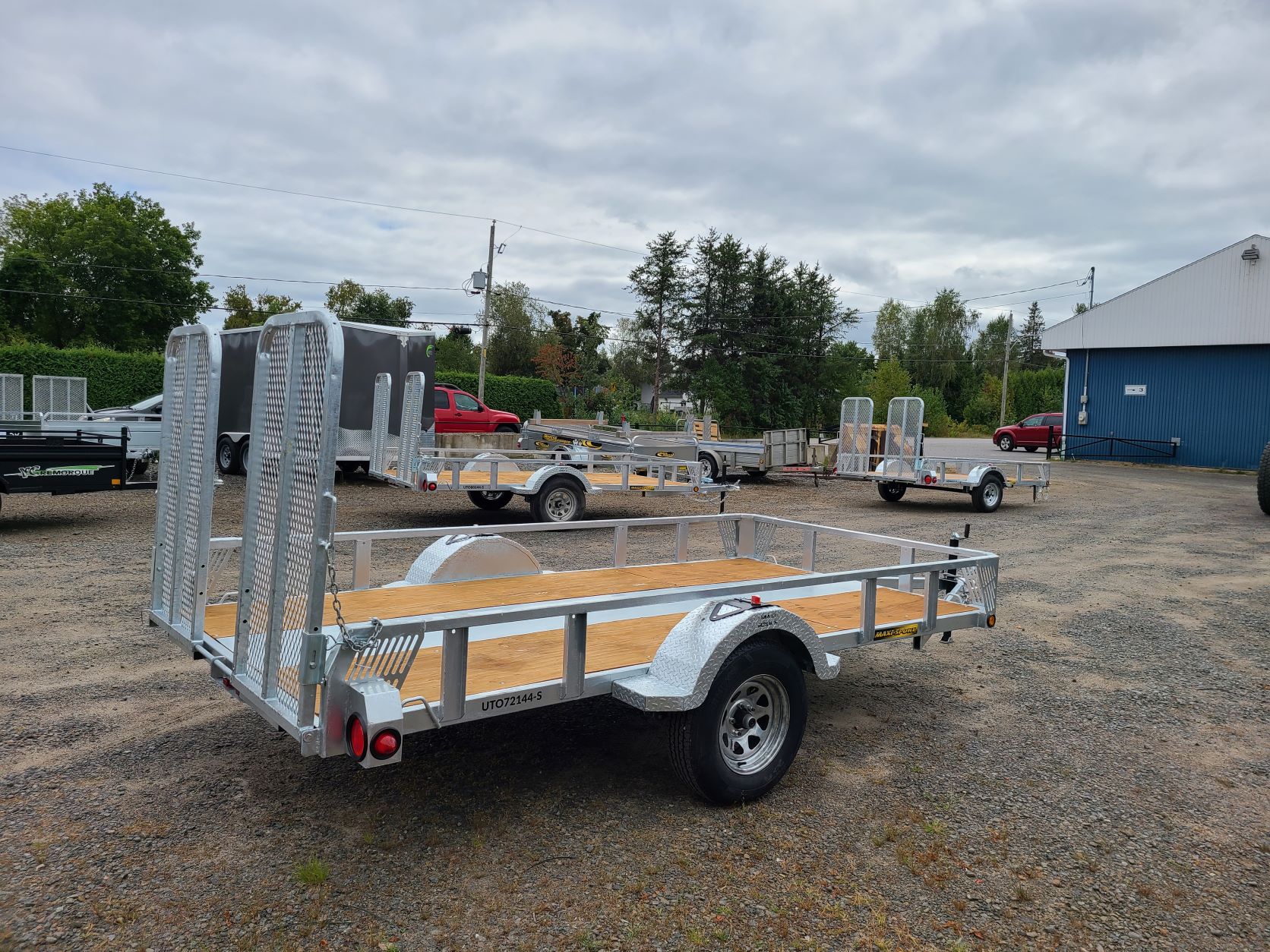 Une remorque est garée sur un terrain en gravier devant un bâtiment.