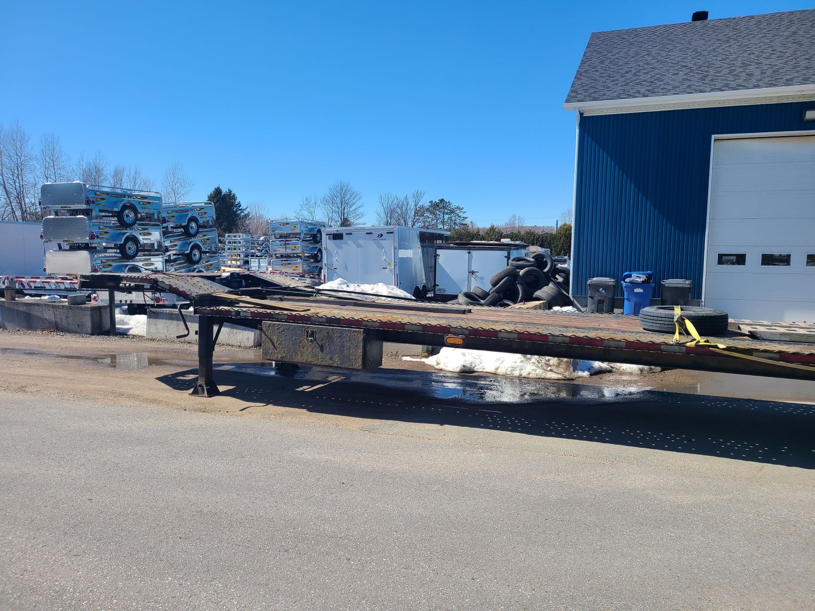 Une remorque à plateau est garée sur le bord de la route.