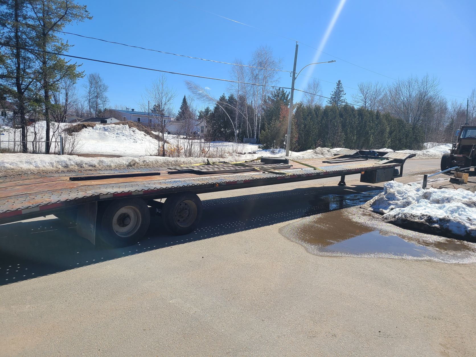 Une remorque à plateau est garée sur le bord de la route