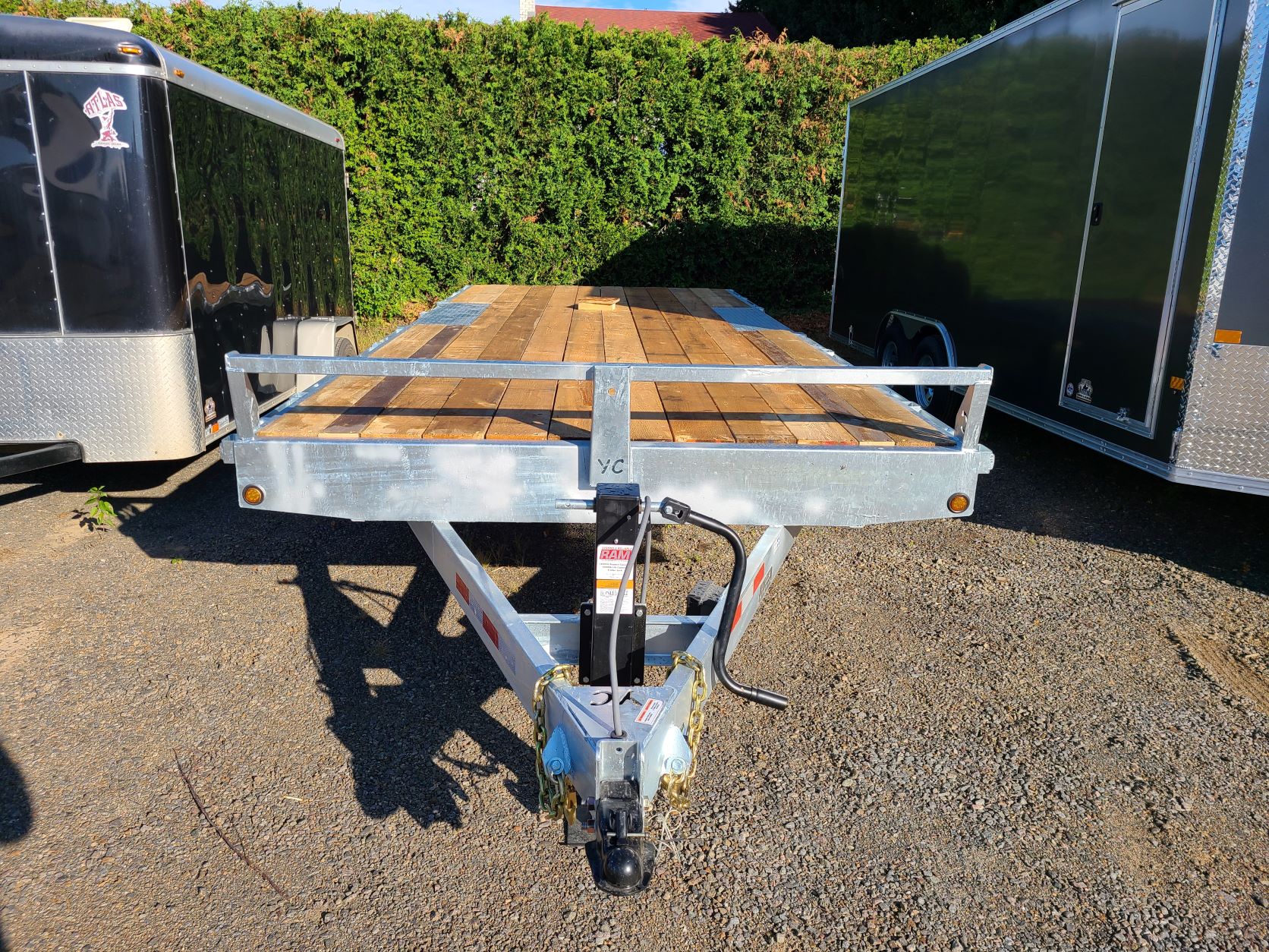 Une remorque avec une terrasse en bois est garée sur un terrain en gravier.