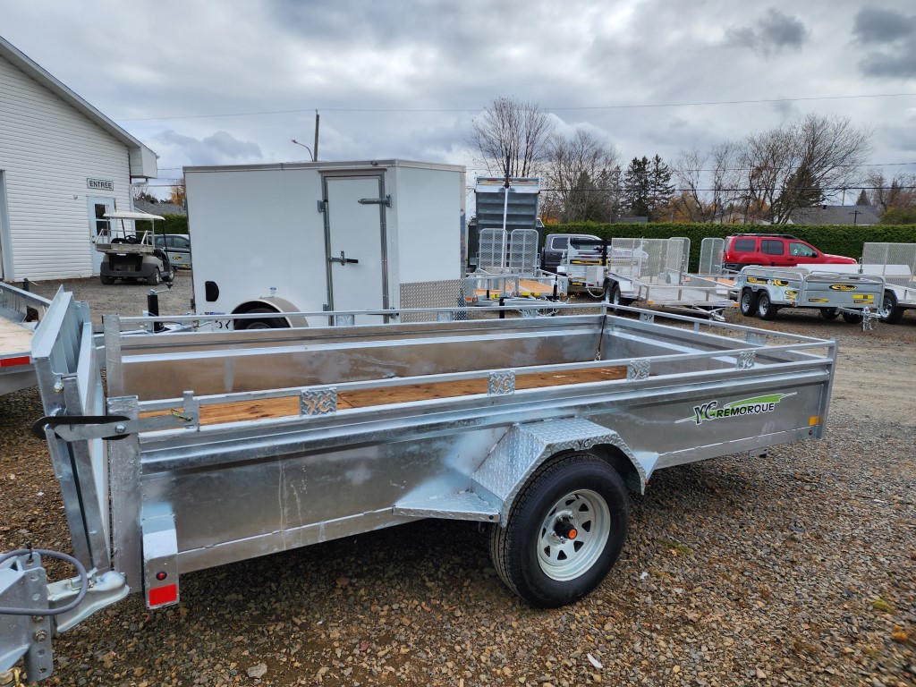 Une remorque est garée sur un terrain en gravier devant un bâtiment.