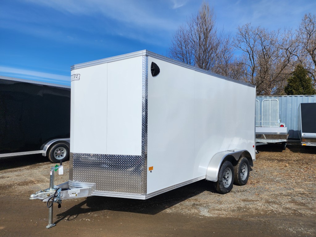 Une remorque blanche est garée sur un terrain en terre.