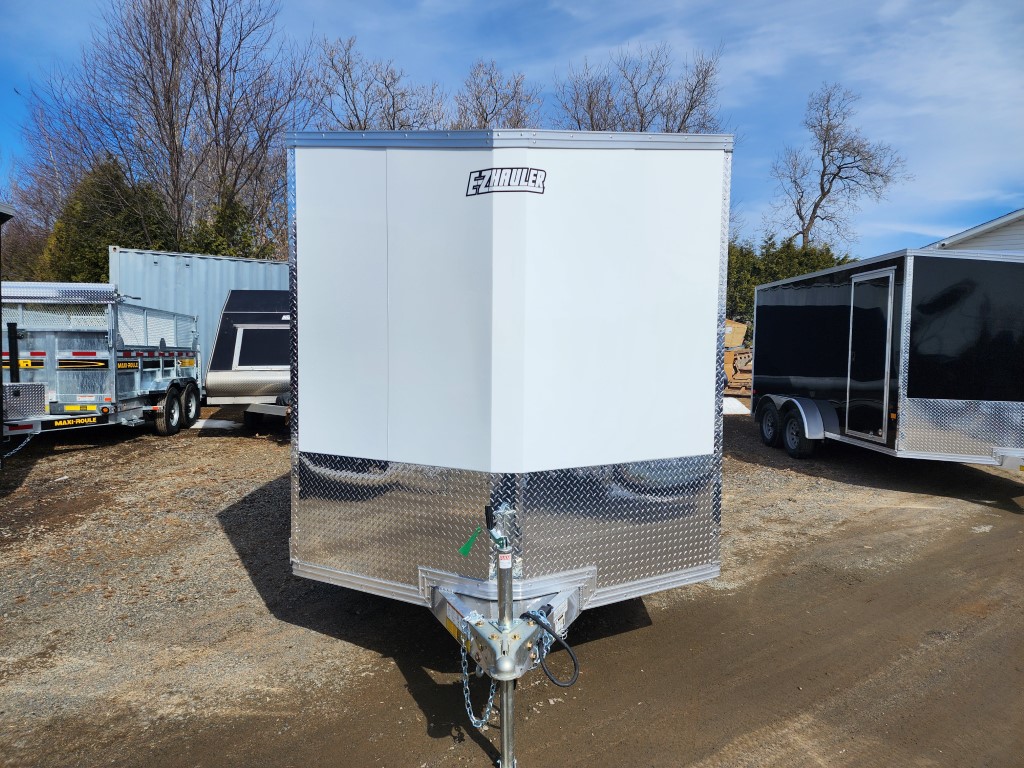 Une remorque blanche est garée sur un parking à côté d'une remorque noire.
