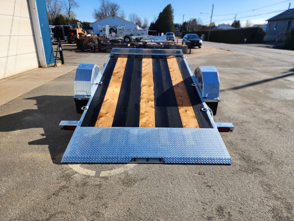 Une remorque avec un pont en bois est garée sur le bord de la route.