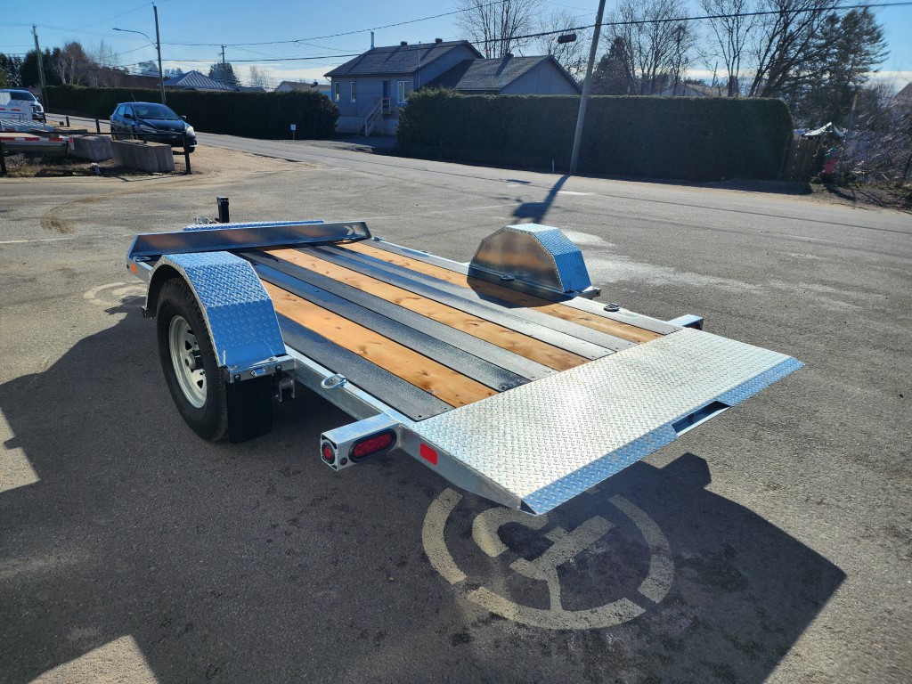 Une remorque de moto est garée sur un parking.
