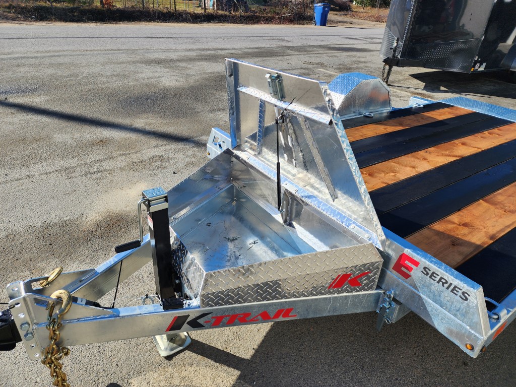 Une remorque avec une boîte à outils attachée est garée sur le bord de la route.