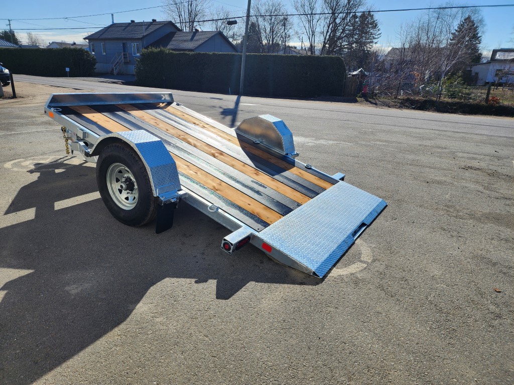 Une remorque de moto est garée sur le bord de la route.
