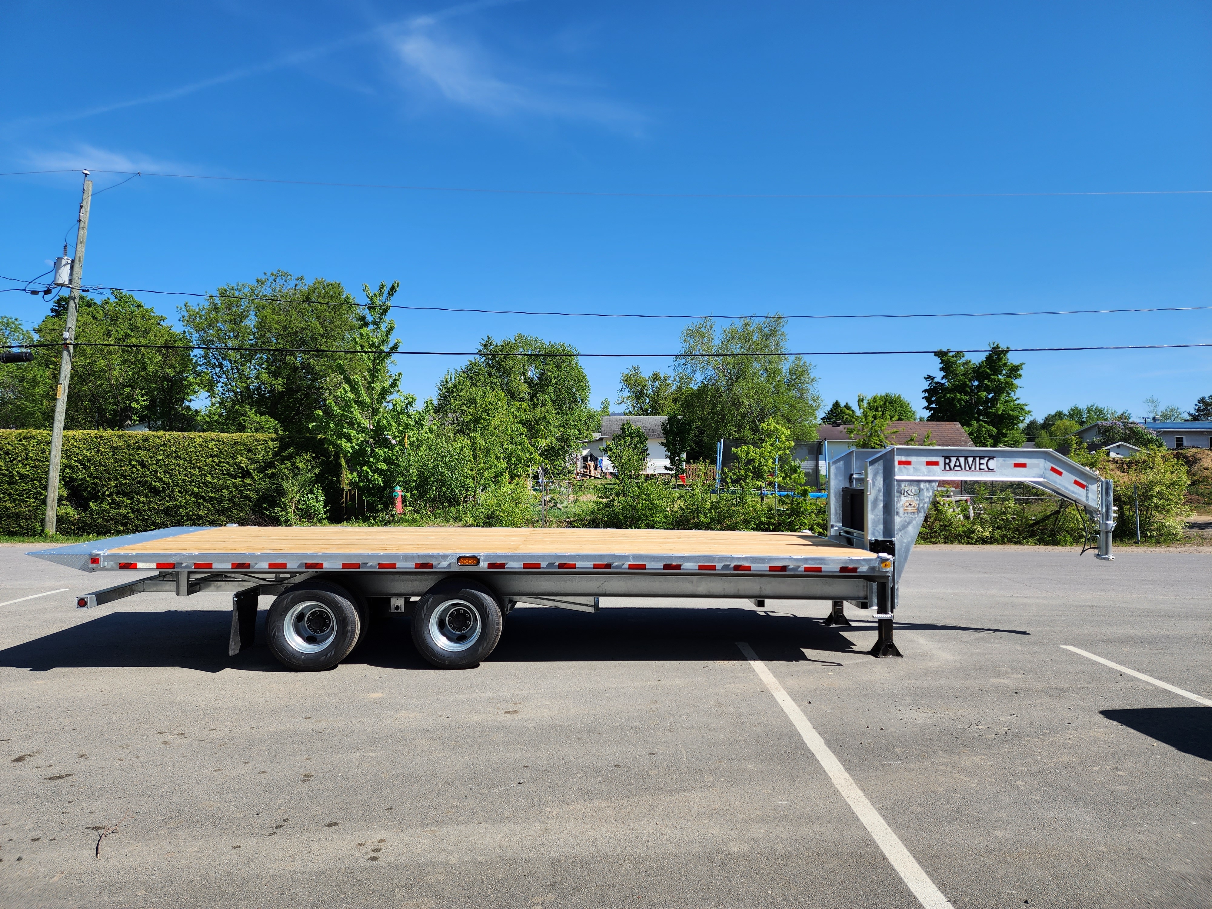 Une remorque à plateau est garée sur un parking.