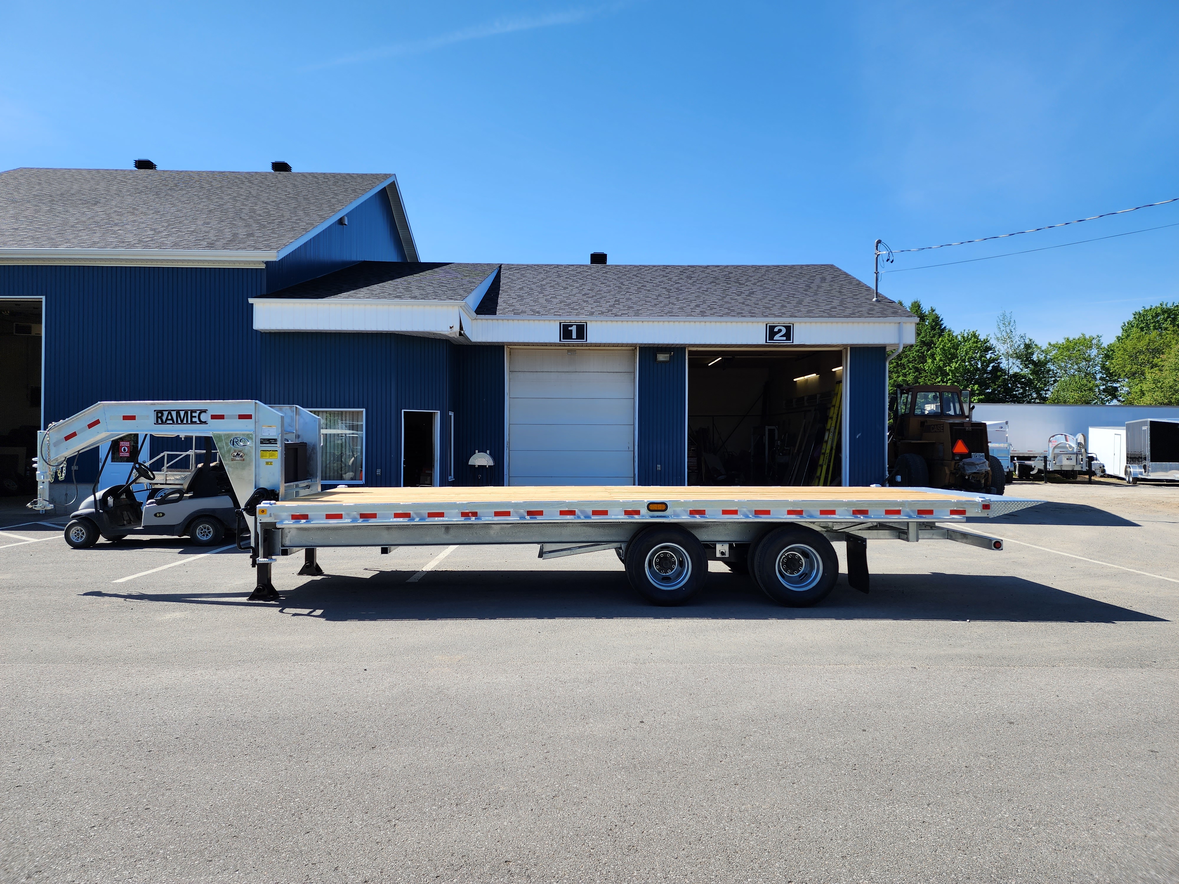 Une remorque à plateau est garée devant un bâtiment.