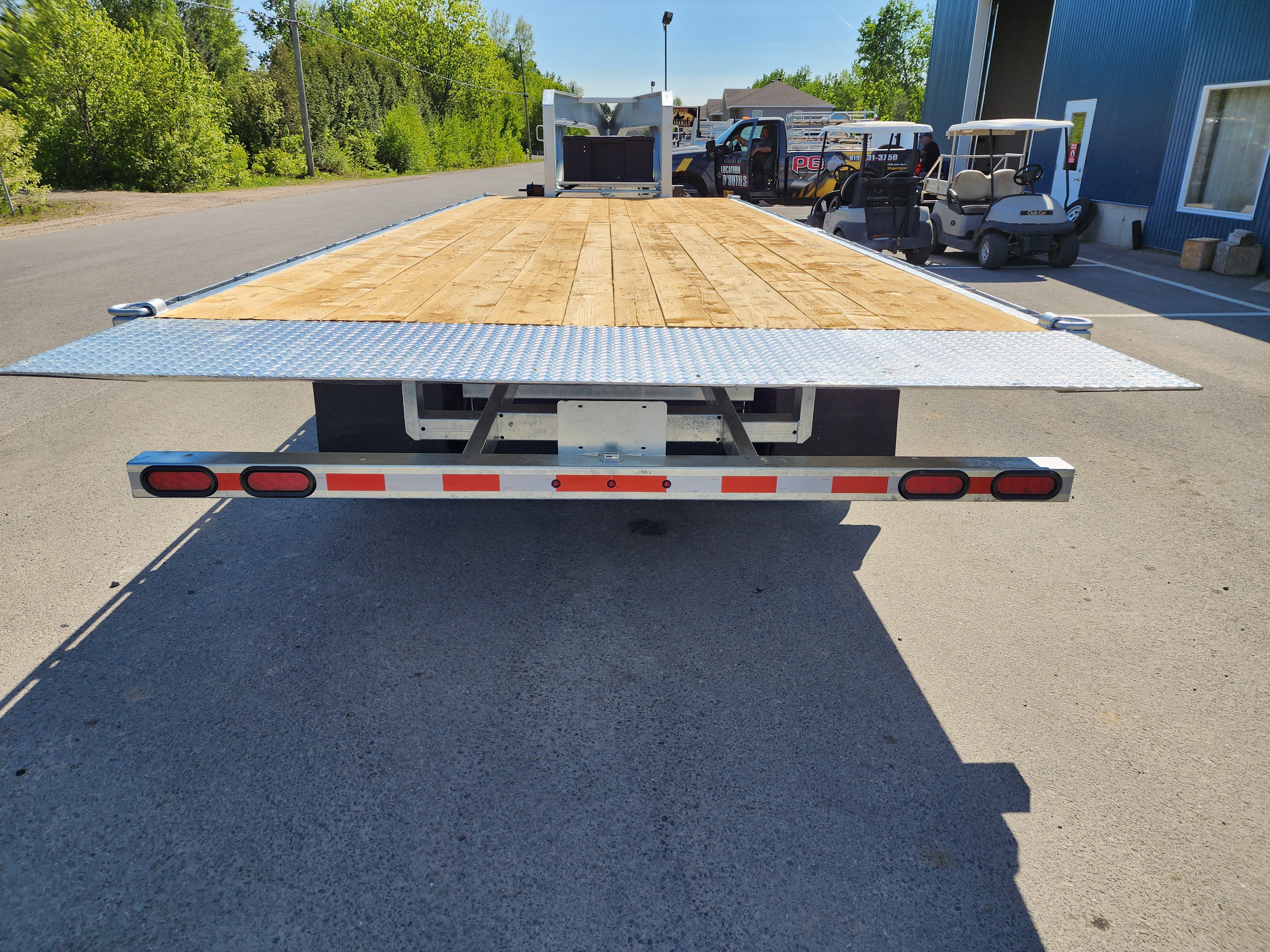 Une remorque à plateau est garée sur le bord de la route.