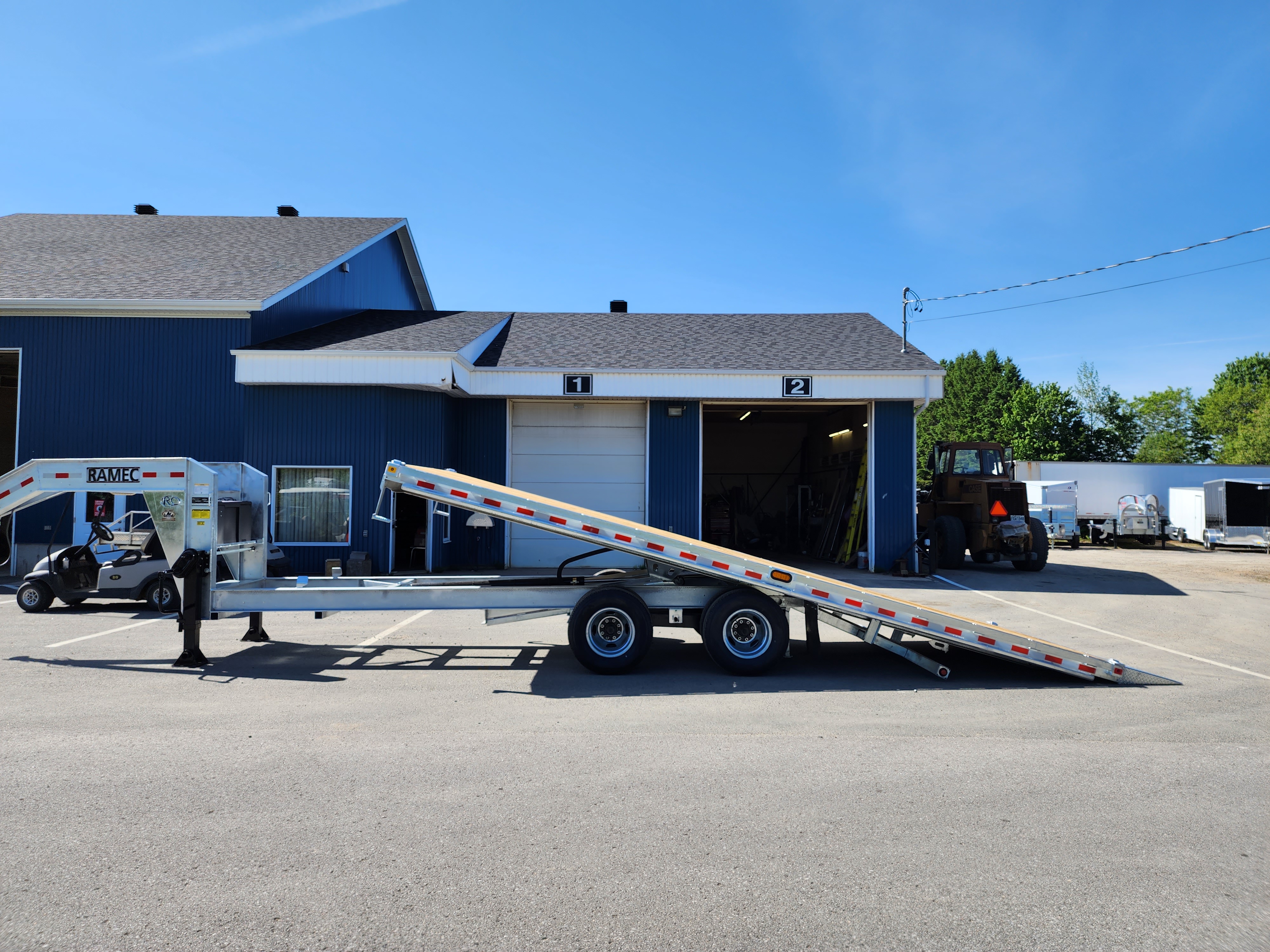 Une remorque à plateau est garée devant un bâtiment.