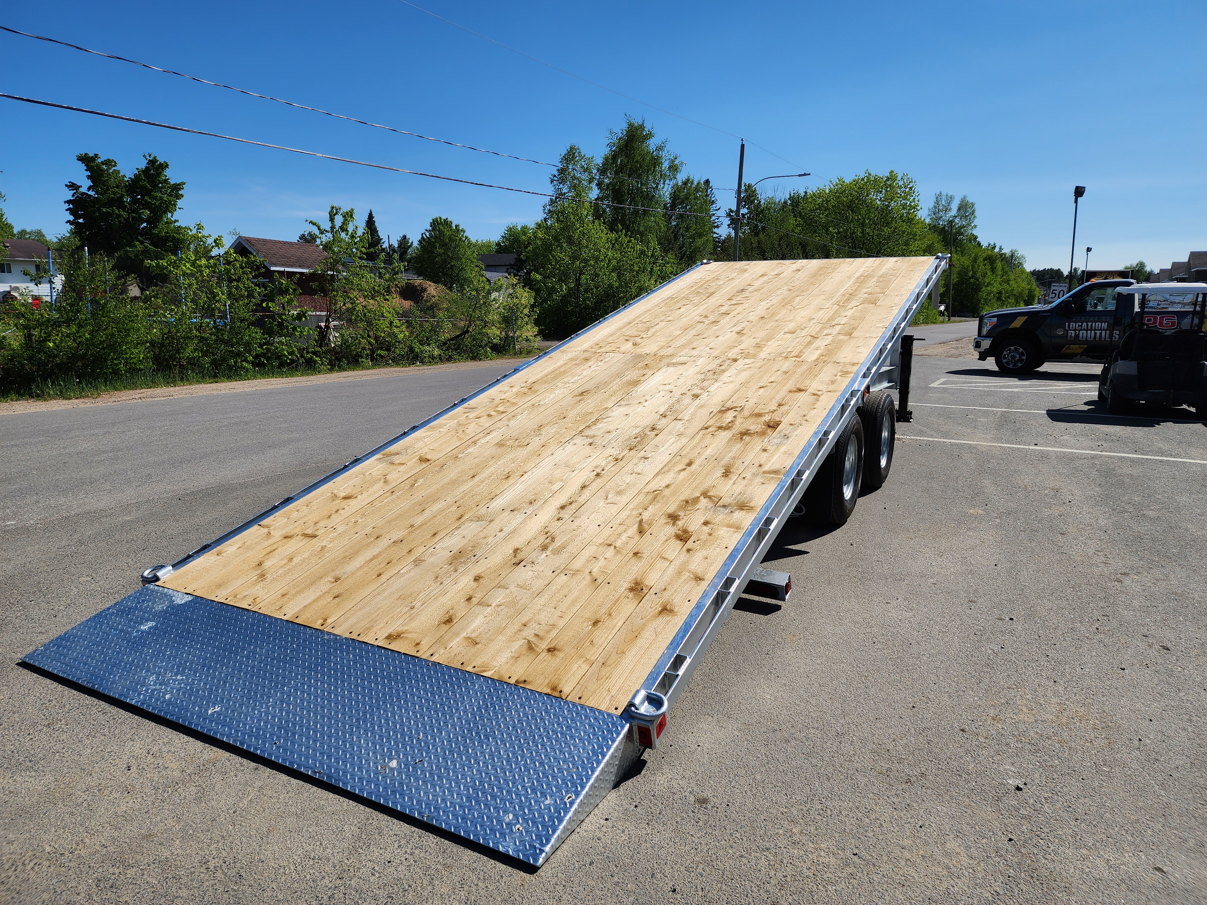 Une remorque à plateau est garée sur le bord de la route.