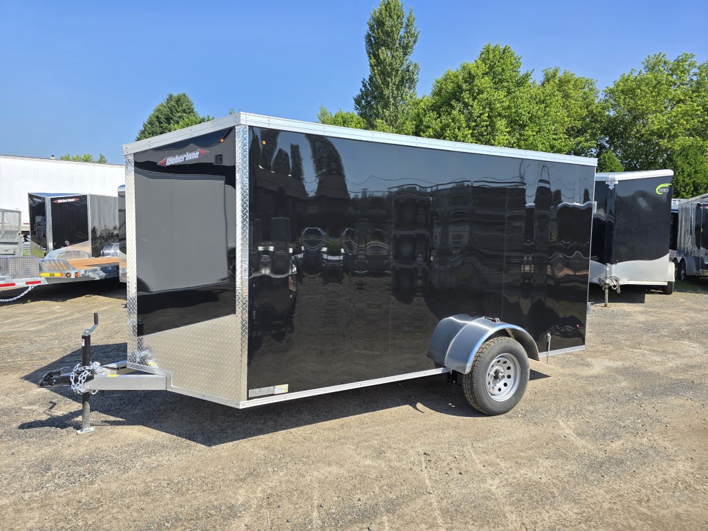 Une remorque noire est garée sur un parking.