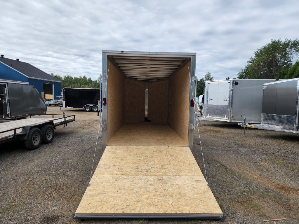 Une remorque avec un plancher en bois est garée sur un parking.