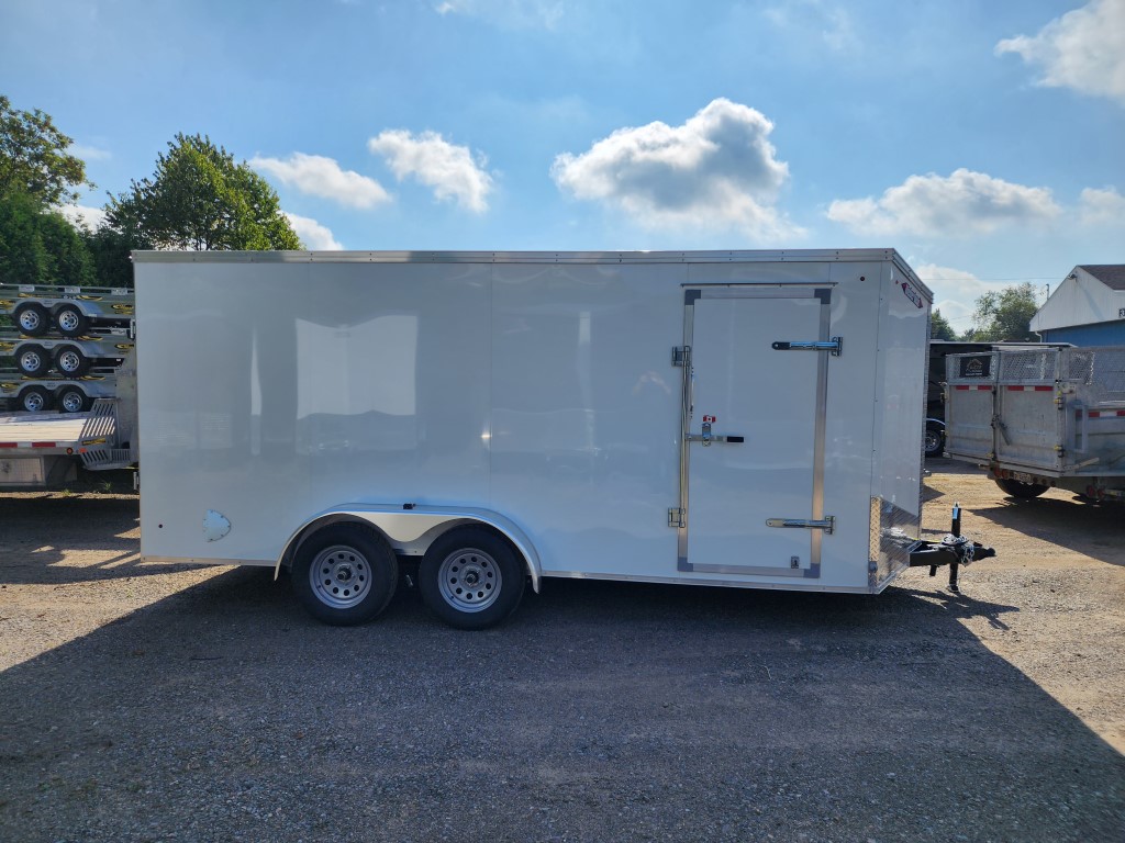 Une remorque blanche est garée sur un terrain en gravier.