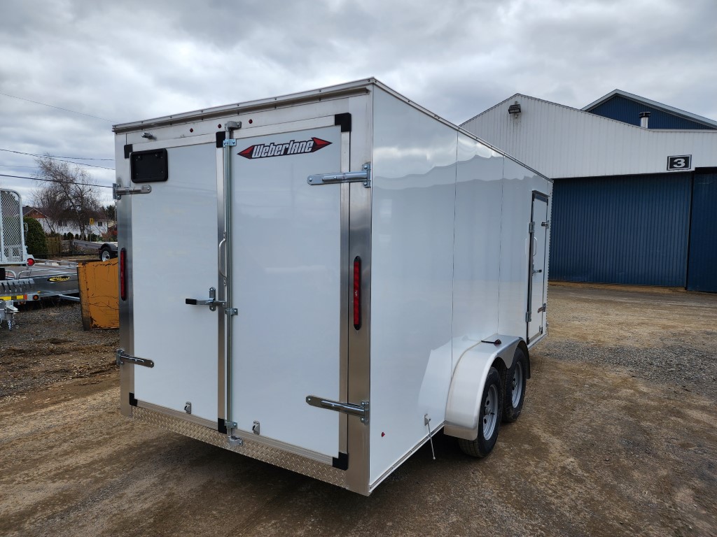 Une remorque blanche est garée devant un bâtiment.