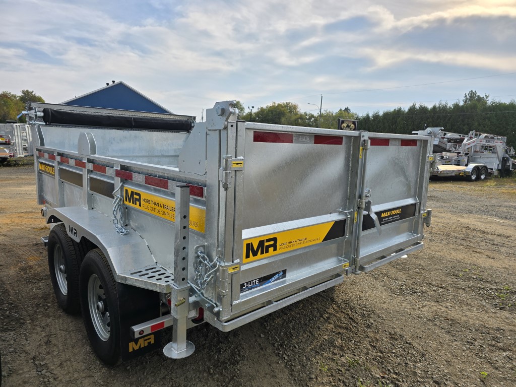Une remorque à benne basculante est garée sur un terrain en gravier.