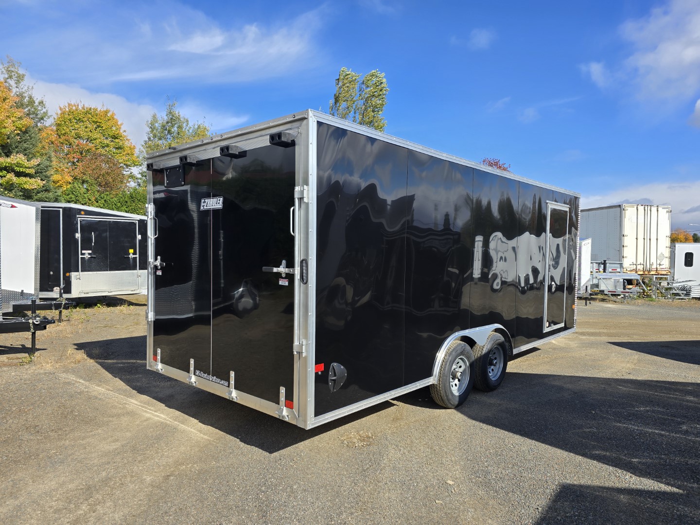 Une remorque noire est garée sur un parking.