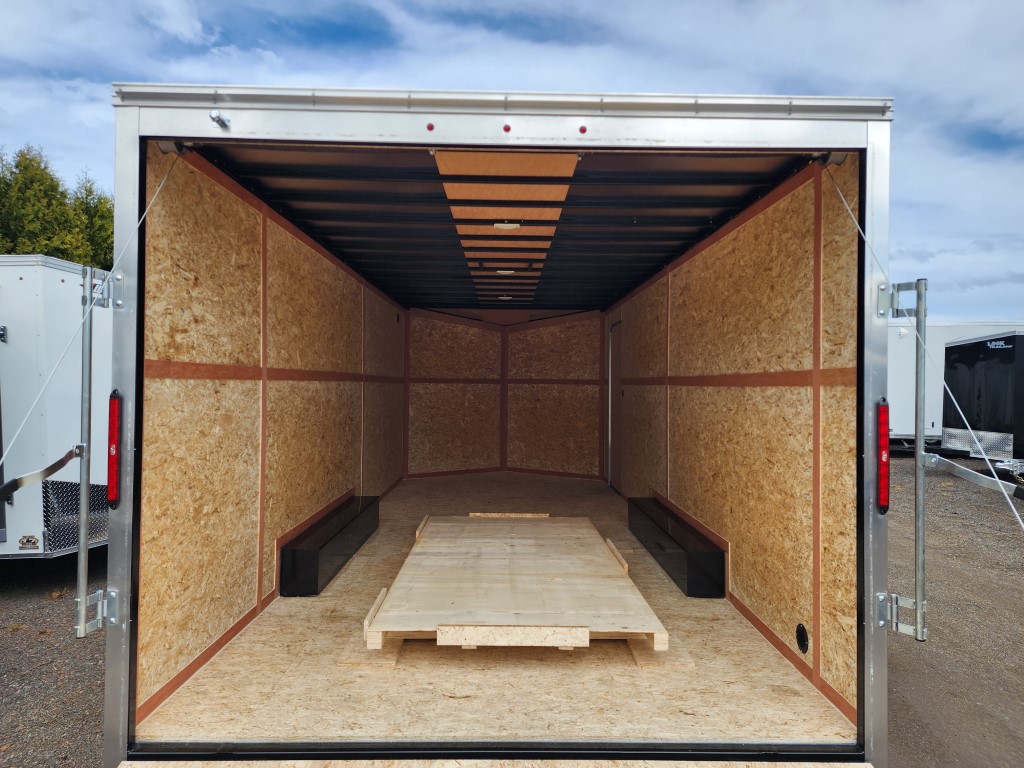 L'intérieur d'une remorque avec la porte ouverte et une palette en bois sur le sol.
