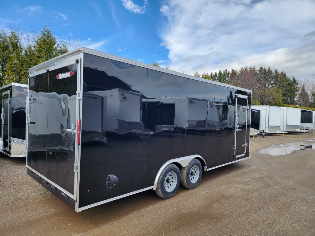 Une remorque noire est garée sur un parking.