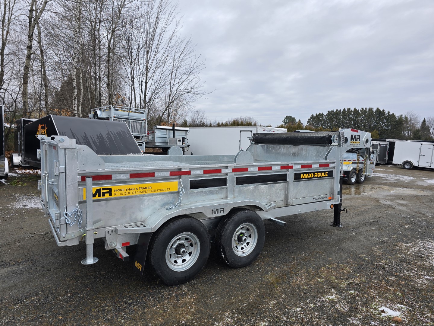 Une remorque à benne basculante est garée dans un parking.