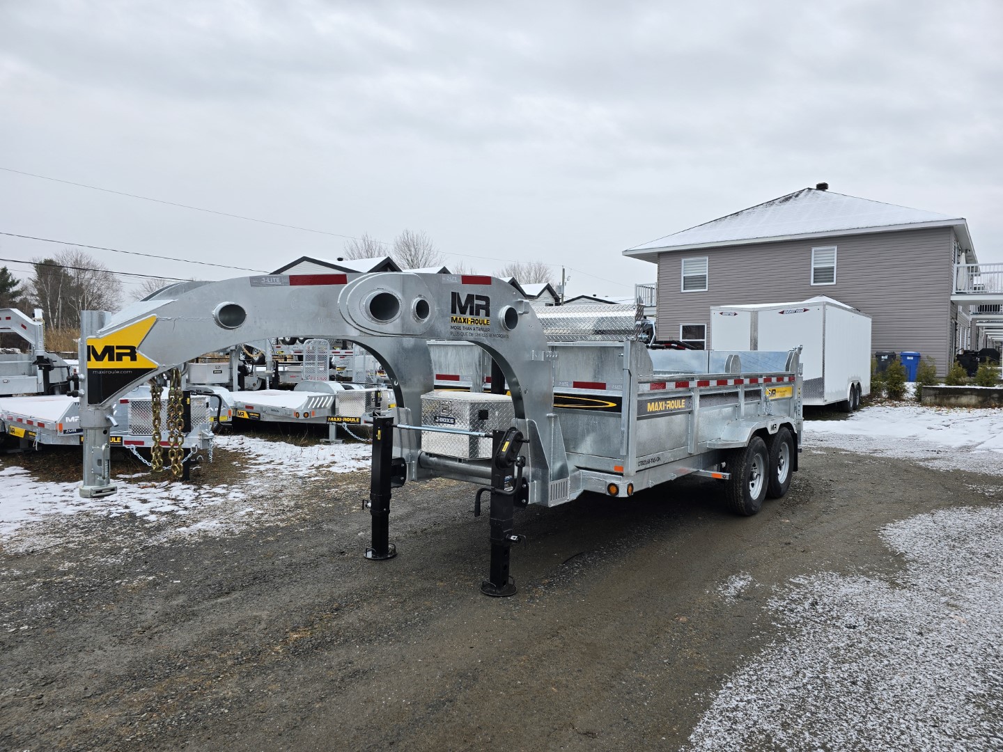 Une remorque est garée dans la neige devant une maison.