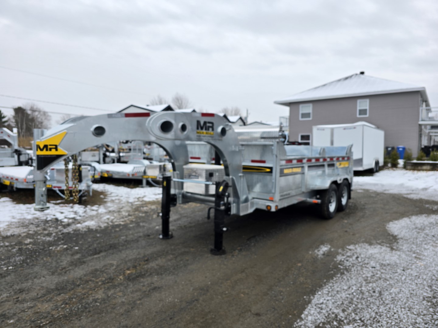 Une remorque est garée dans la neige devant une maison.