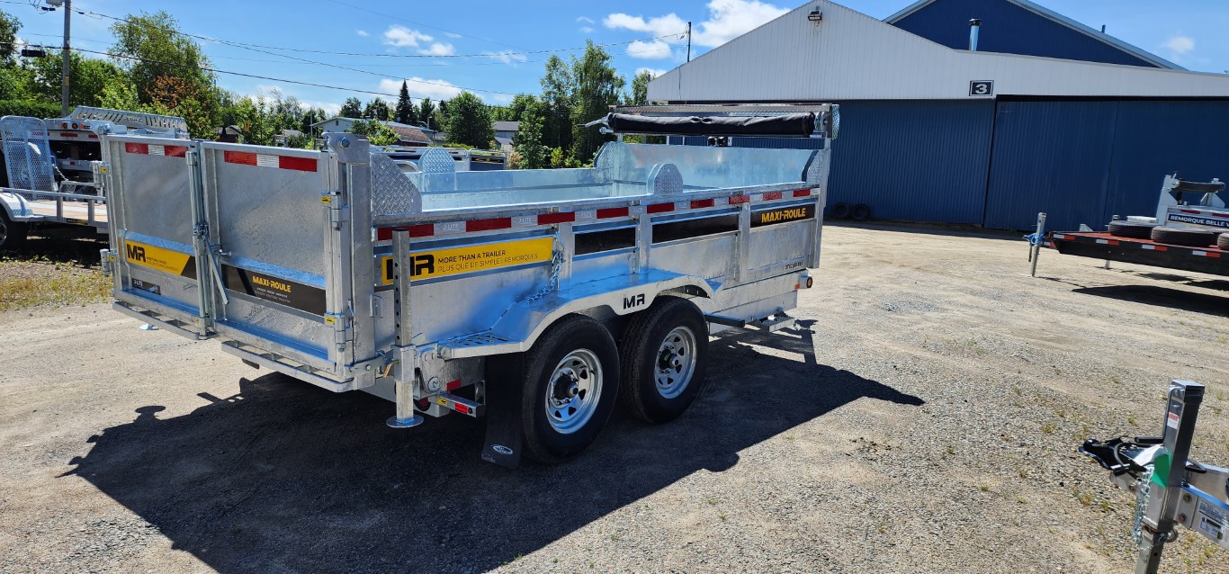 Une remorque est garée sur un terrain en gravier devant un bâtiment.