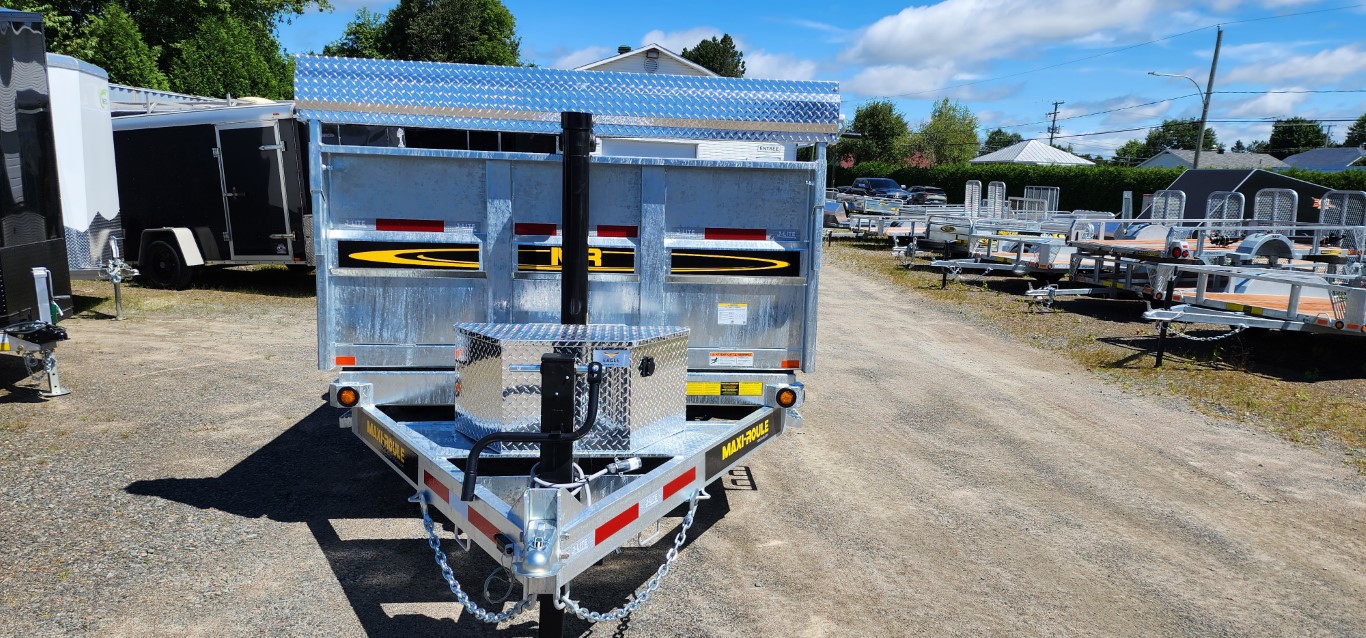Une remorque argentée est garée sur un terrain en gravier.