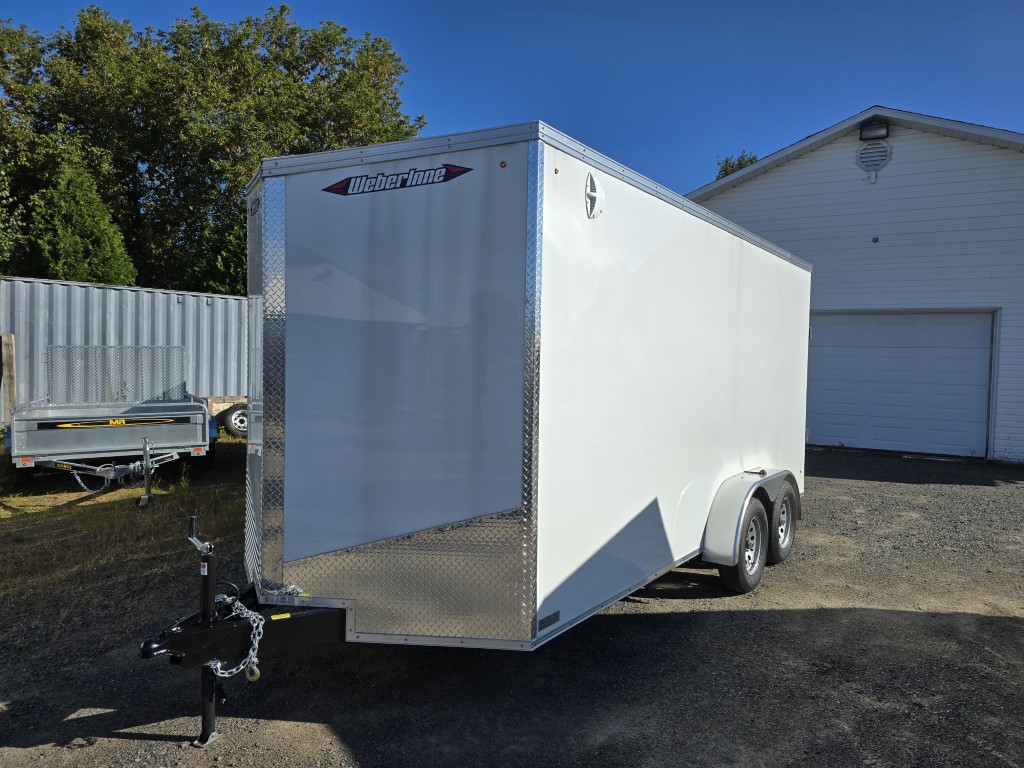 Une remorque blanche est garée devant un garage.