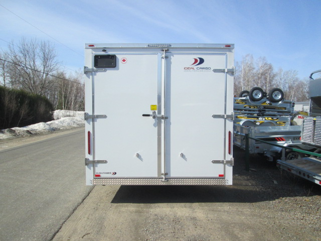 Une remorque blanche est garée sur le bord de la route.