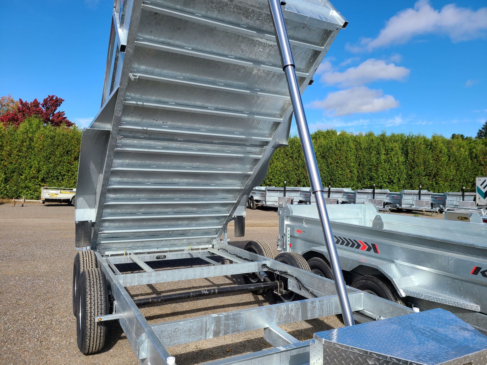 Une remorque à benne basculante avec le couvercle ouvert est garée sur un parking.