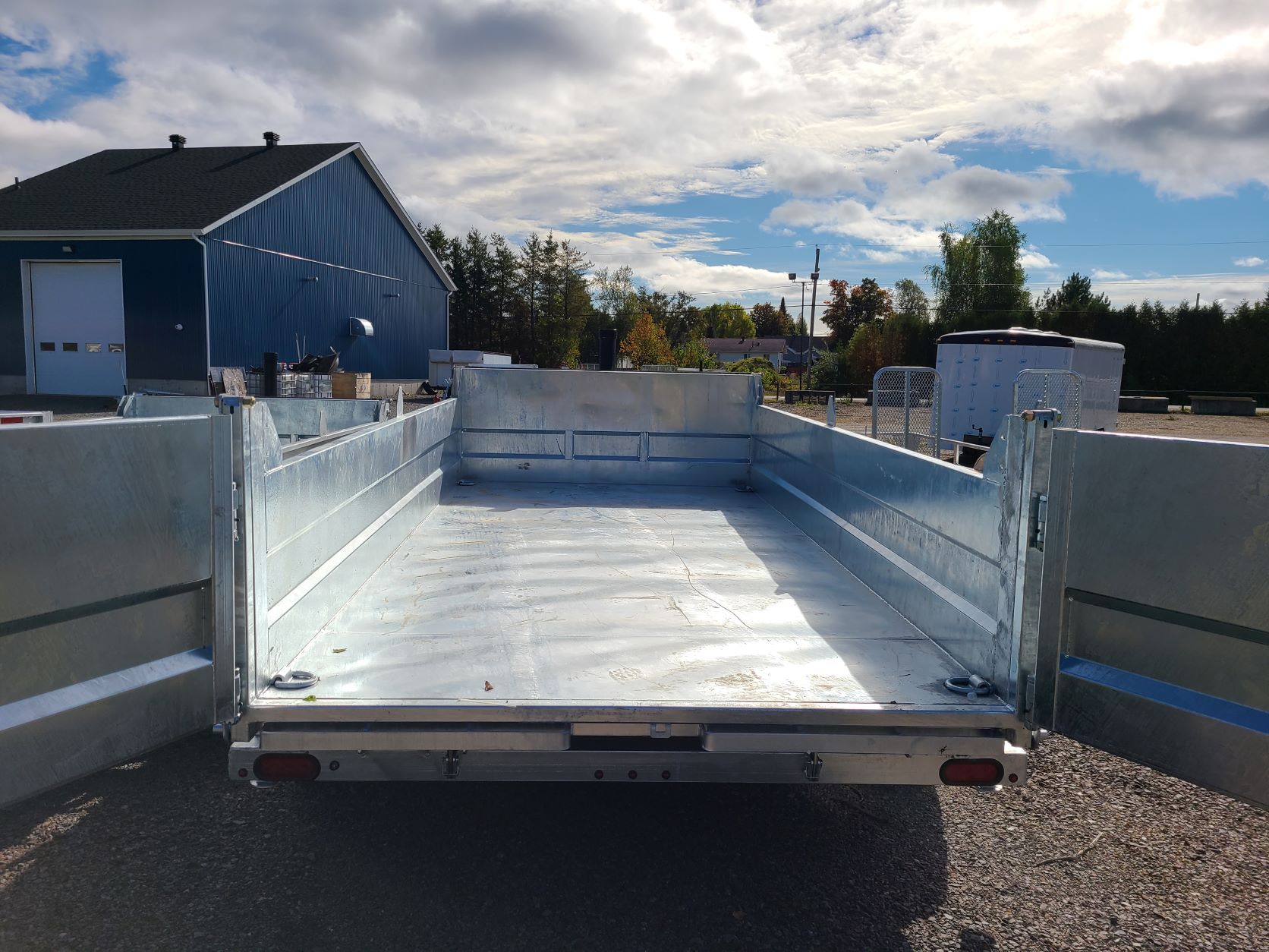 Une remorque métallique est garée devant un bâtiment