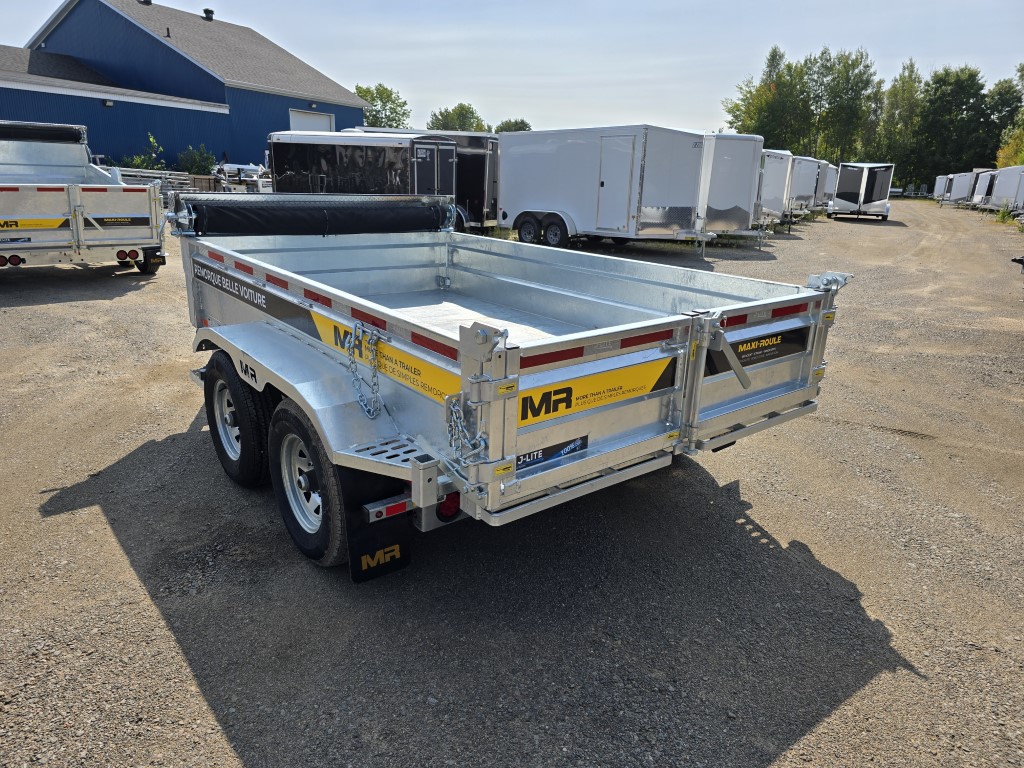 Une remorque est garée sur un terrain en gravier devant un bâtiment.